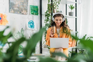 femme travaillant sur son ordinateur avec un casque audio et un café à la main